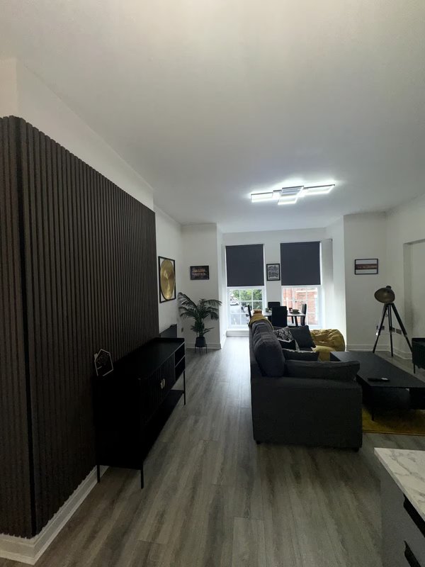 Modern living room with black furniture, wooden flooring, curtains and tripod camera