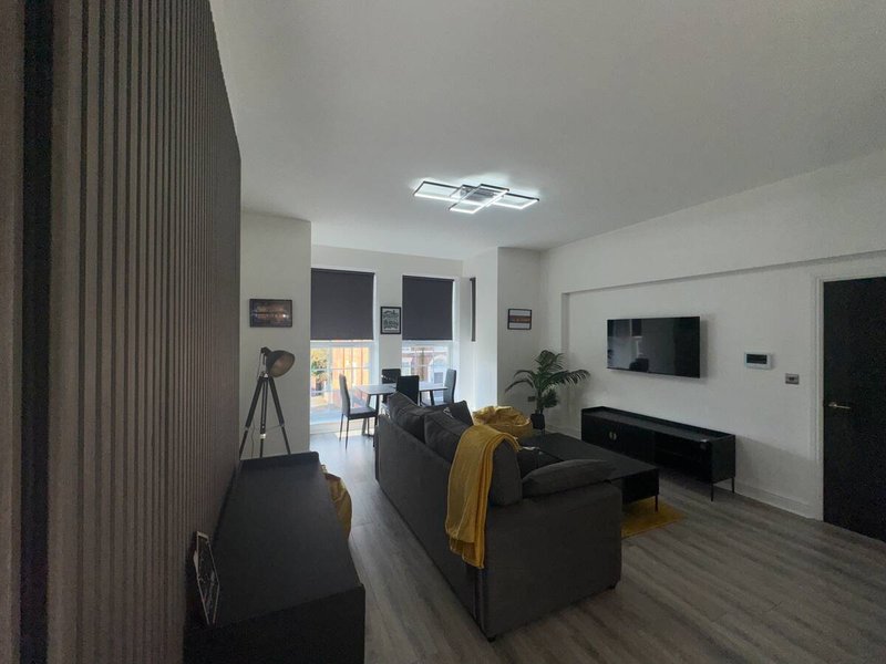 Modern living room with black sofa, TV wall mount, wooden flooring and open-plan layout