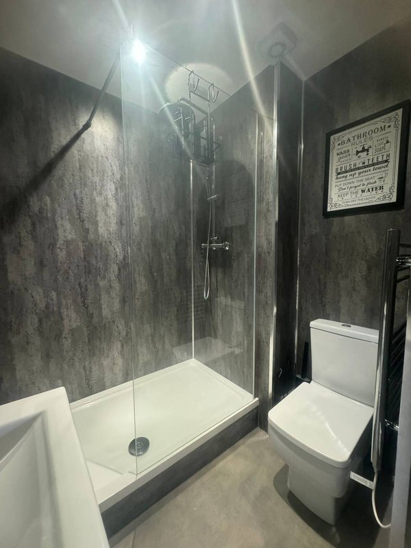 Modern bathroom with walk-in shower, toilet, and framed wall art