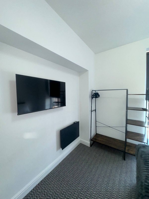 Modern bedroom with wall-mounted TV, metal-frame bed and geometric patterned carpet flooring