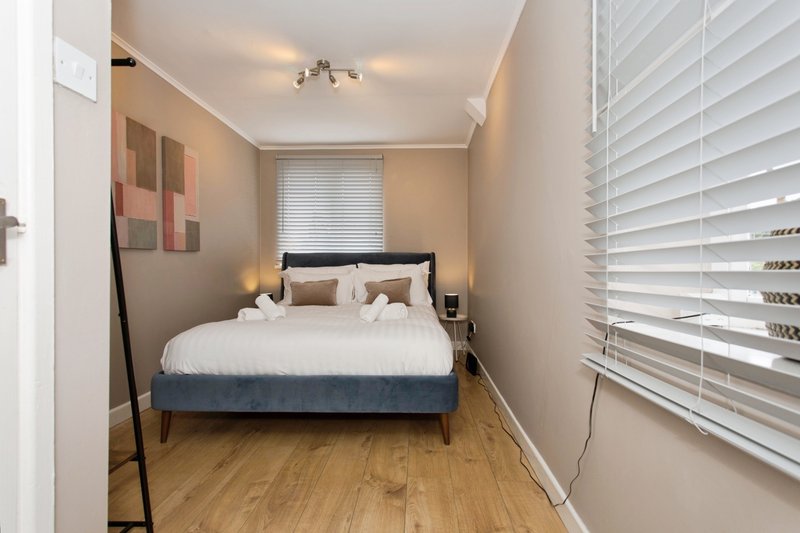 Compact bedroom with double bed, wooden floor, white shutters and wall art