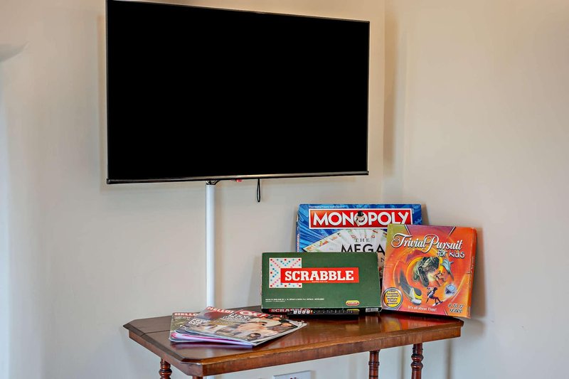 Wall-mounted TV above wooden table with board games and magazines