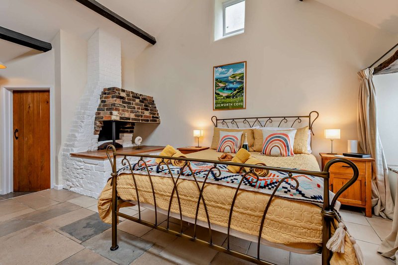 Bright bedroom with metal bed frame, fireplace, wooden desk, and bohemian decor