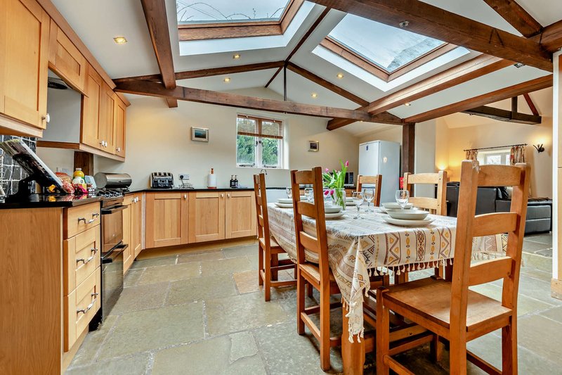 Open-plan kitchen and dining area with wooden cabinets, skylight, and dining table with chairs
