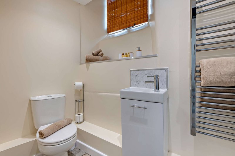 Modern bathroom with toilet, vanity sink, heated towel rail and window