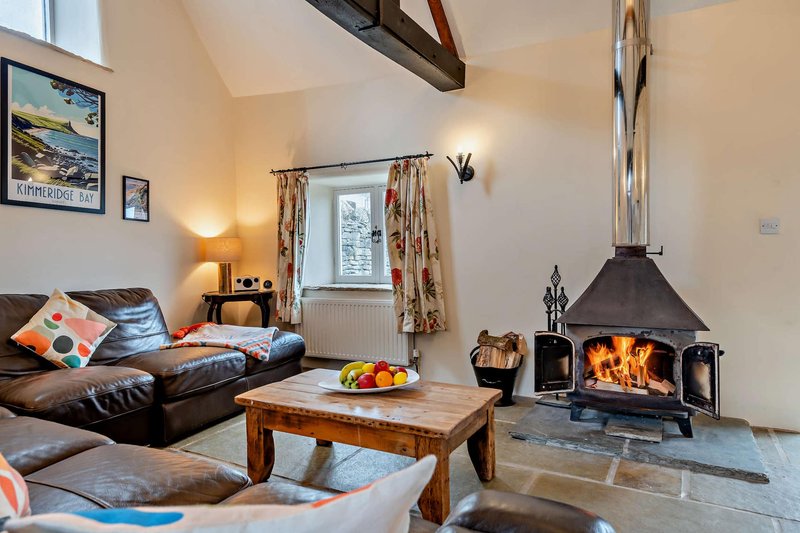 Spacious living room with leather sofa, wooden coffee table, active fireplace and framed wall art