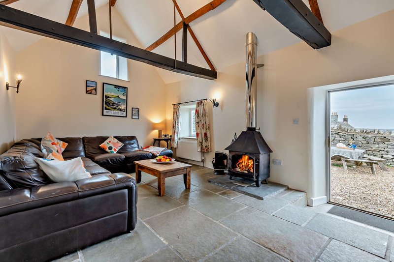 Modern living room with black leather sofa, wood beams, wood-burning stove and patio doors