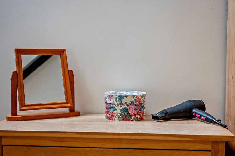 Wooden dresser with mirror, decorative container, and hair dryer