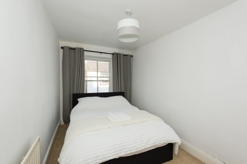 Bright bedroom with single bed, white bedding, gray curtains and ceiling light