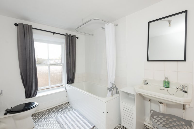Modern bathroom with white bathtub, shower enclosure, pedestal sink and mirror
