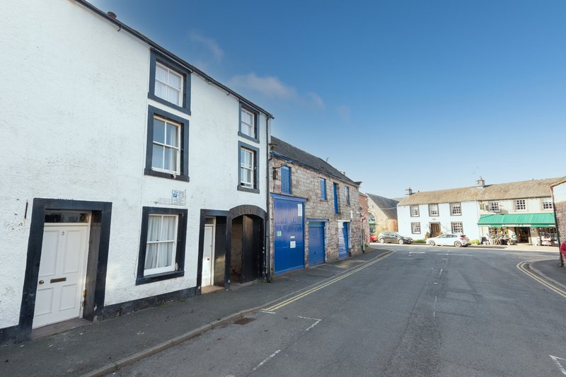 Street-facing exterior of white and stone terraced houses with blue doors and windows