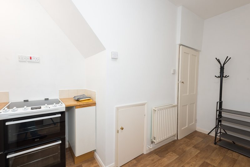 Kitchen area with double oven, white cabinetry, wooden worktop and coat stand
