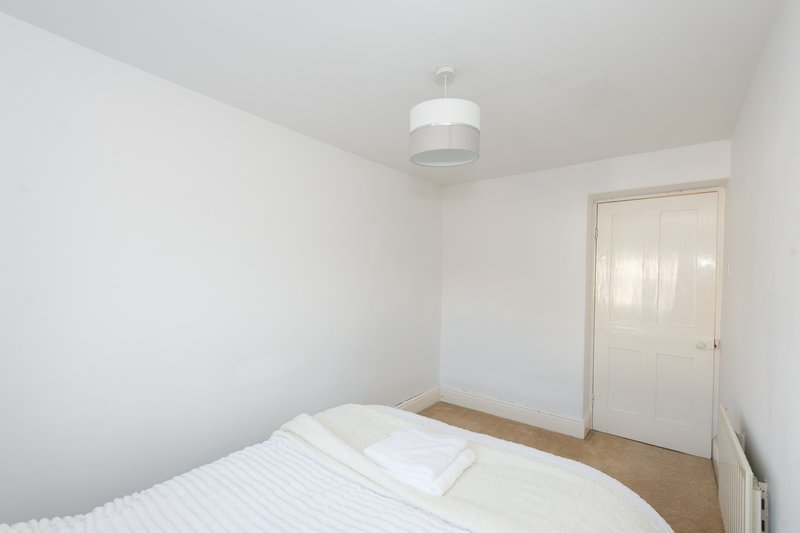 Bright bedroom with double bed, white bedding, pendant light, and cream door