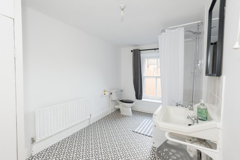Clean modern bathroom with toilet, shower cubicle, sink and patterned floor tiles