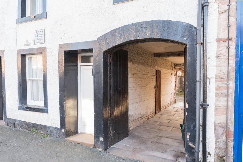 Exterior building entrance with black wooden door and arched passageway leading inside