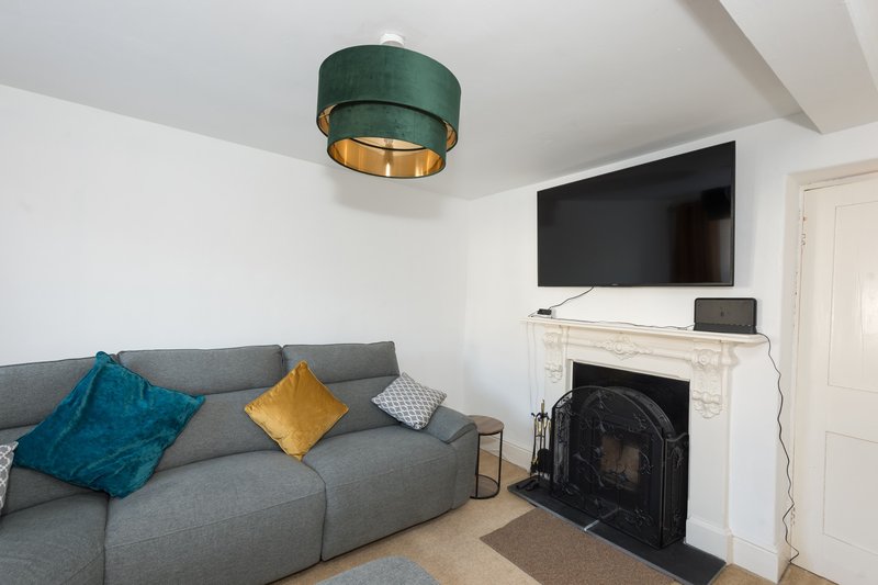 Modern living room with gray sofa, colorful cushions, fireplace and wall-mounted TV