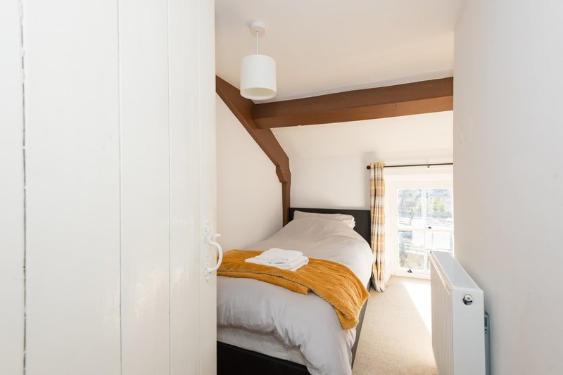 Compact bedroom with double bed, wooden beam ceiling, and access to patio doors