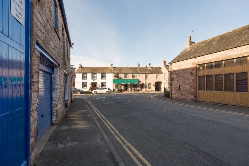 Stone village street with terraced cottages, blue door on left, clear daytime view