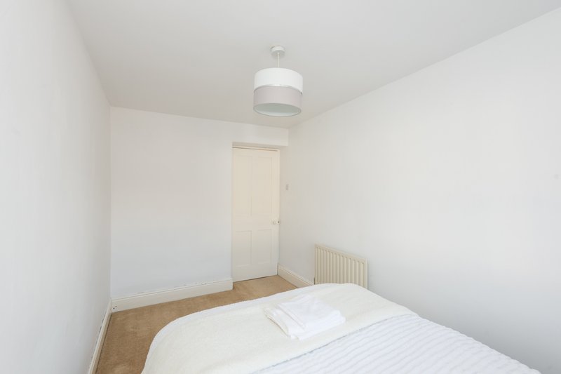 Bright bedroom with single bed, white bedding, pendant light and cream door