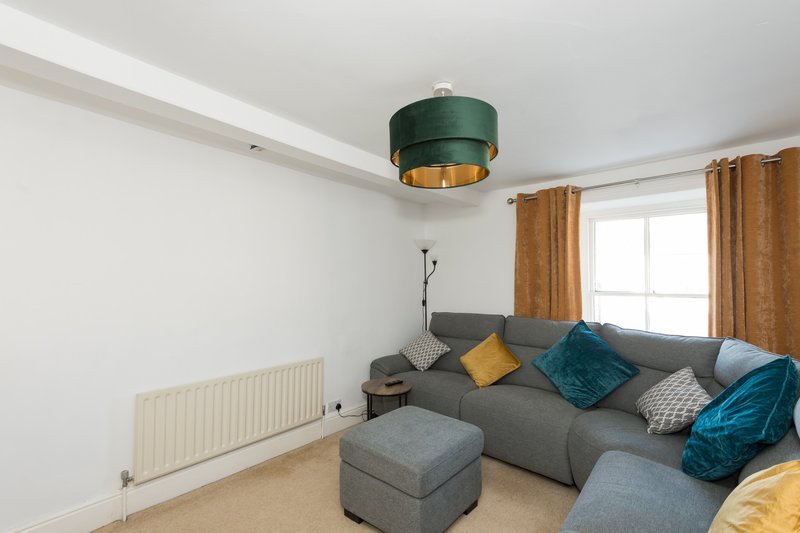 Modern living room with gray sectional sofa, colorful cushions, green pendant lamp and window