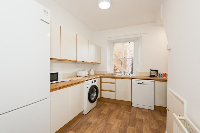 Modern kitchen with white cabinetry, wooden countertops, washing machine and wooden flooring