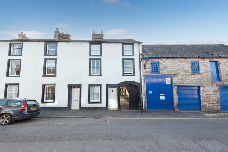 White and stone terraced houses with blue doors and parked car on street