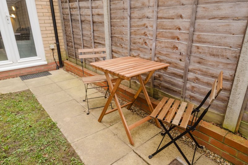 Patio garden with wooden dining table, chairs, fencing and paved area