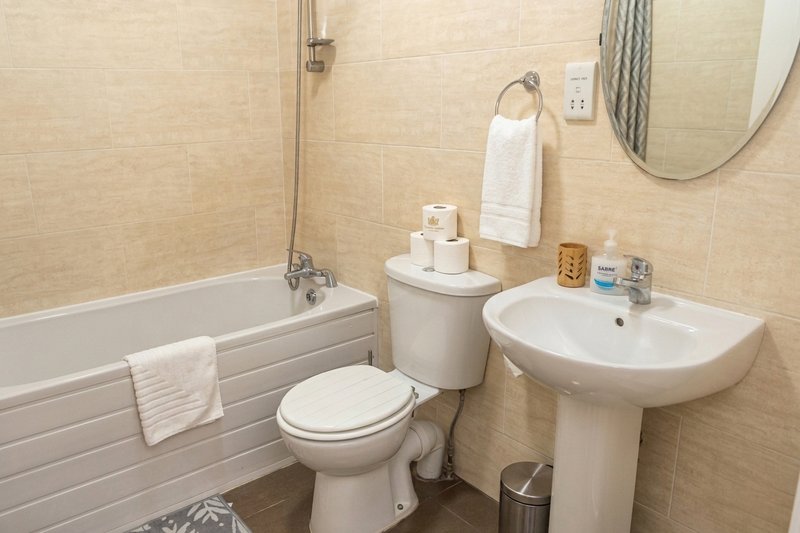 Bathroom with bathtub, toilet, pedestal sink, mirror and towel rail