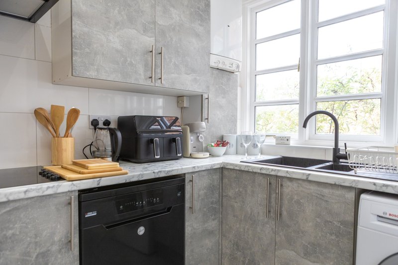 Modern kitchen with grey cabinetry, black oven, sink, and window overlooking garden