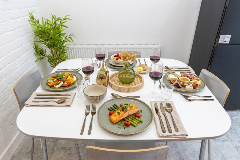 Dining table set for meal with plated food, wine glasses, and fresh plant centerpiece