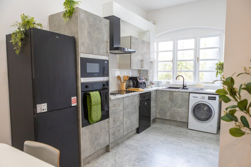 Modern kitchen with black appliances, concrete cabinetry, washing machine, and large windows