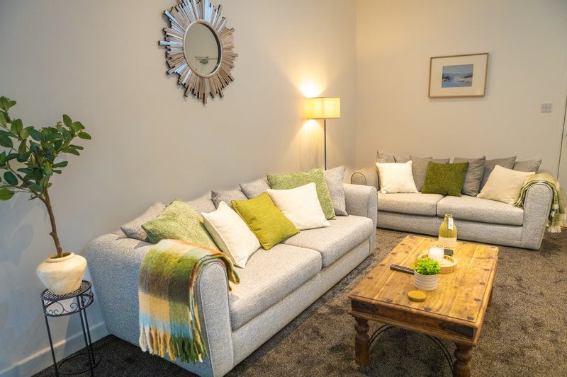 Bright living room with two grey sofas, wooden coffee table, cushions and throws