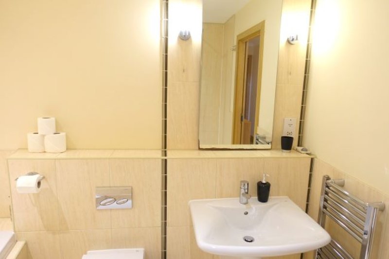 Modern bathroom with white sink, mirror, heated towel rail and toilet roll holder