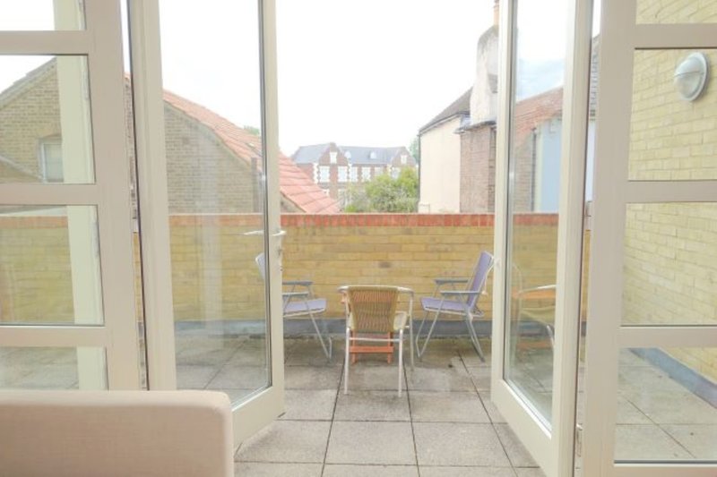 Patio view through open glass doors with table, chairs and surrounding brick walls