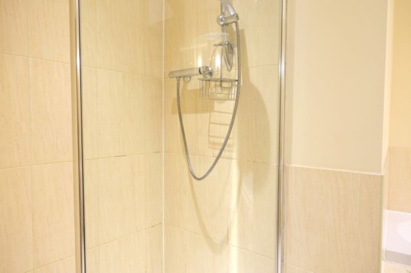 Modern bathroom shower cubicle with chrome fixtures and cream tile walls