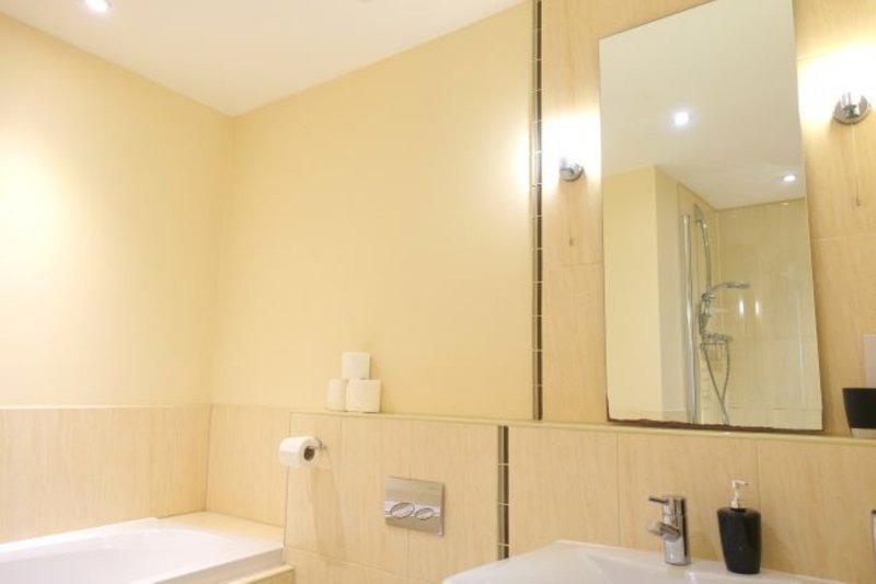 Modern bathroom with pale yellow walls, wooden paneling, large mirror and white sink