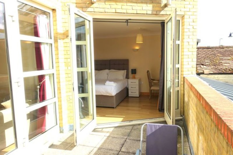Bedroom viewed from terrace with double bed, bedside table, wooden flooring and open patio doors