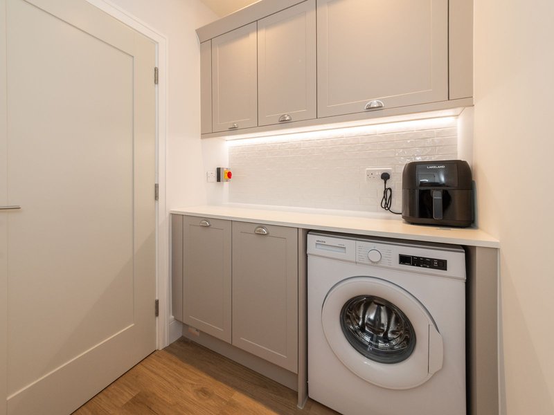 Modern laundry room with washer, dryer, countertop storage and coffee maker