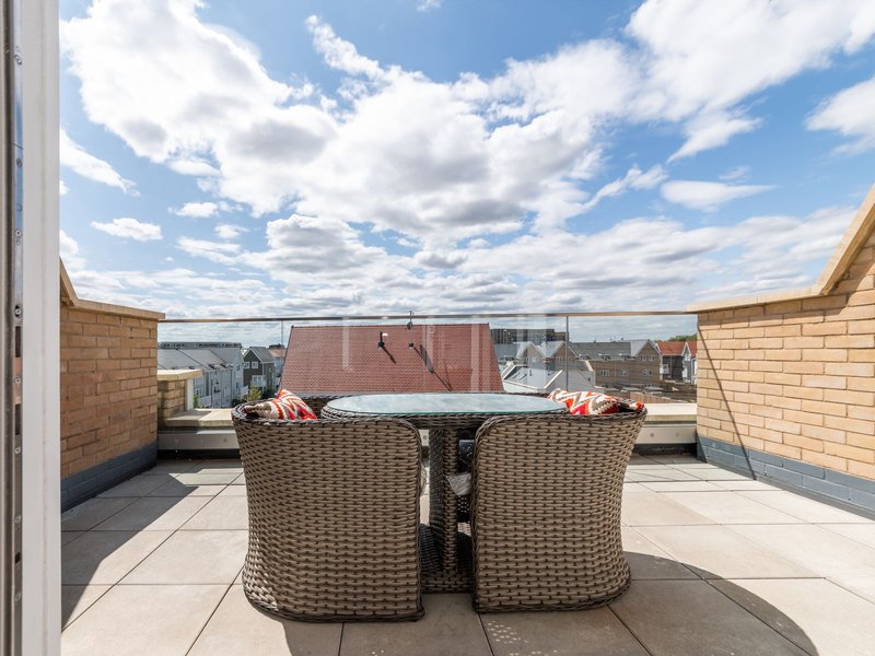 Rooftop terrace with woven chairs, table and panoramic city skyline view