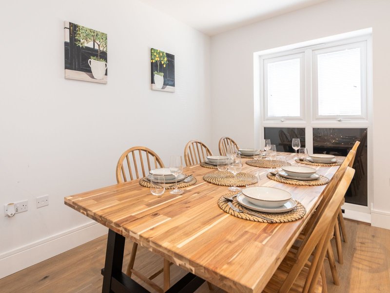 Dining room with wooden table, place settings, Windsor chairs and window view