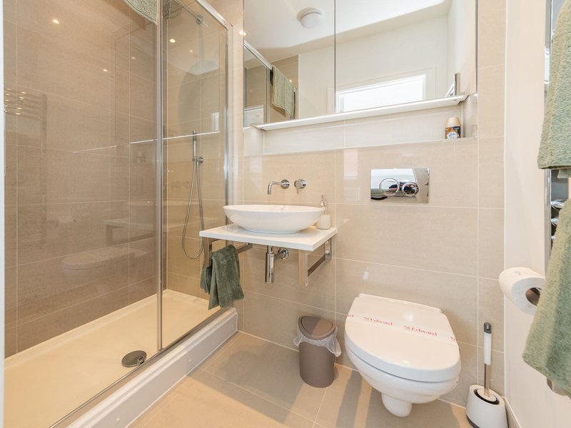 Modern bathroom with walk-in shower, white basin, toilet, mirror and heated towel rail
