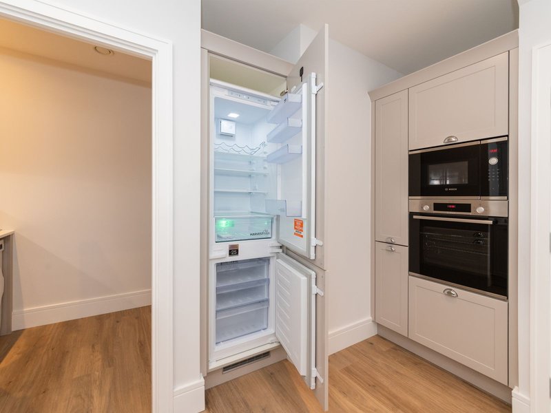 Modern kitchen with integrated appliances, open refrigerator, and wooden flooring