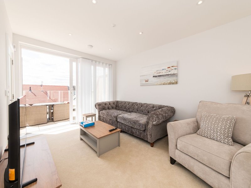 Bright living room with two sofas, wooden coffee table, and glass doors opening to balcony