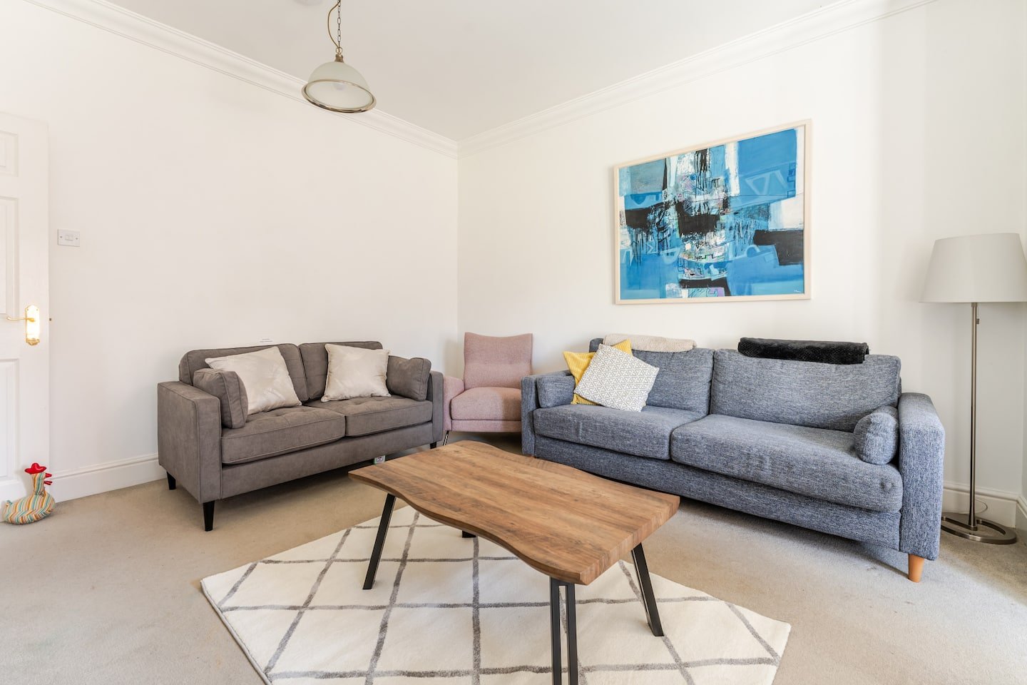 Spacious living room with two sofas, wooden coffee table, and modern wall art