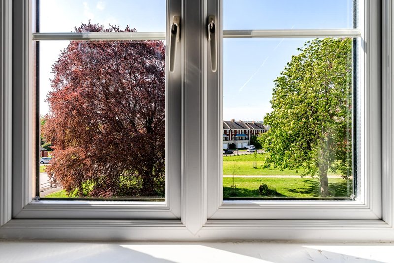 View through open windows of garden with trees and green lawn
