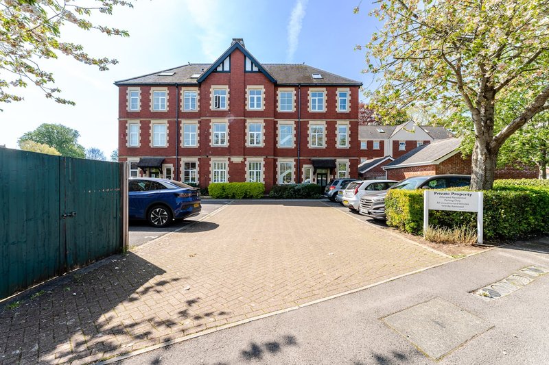 Red brick period property with driveway, parked cars, and mature trees surrounding