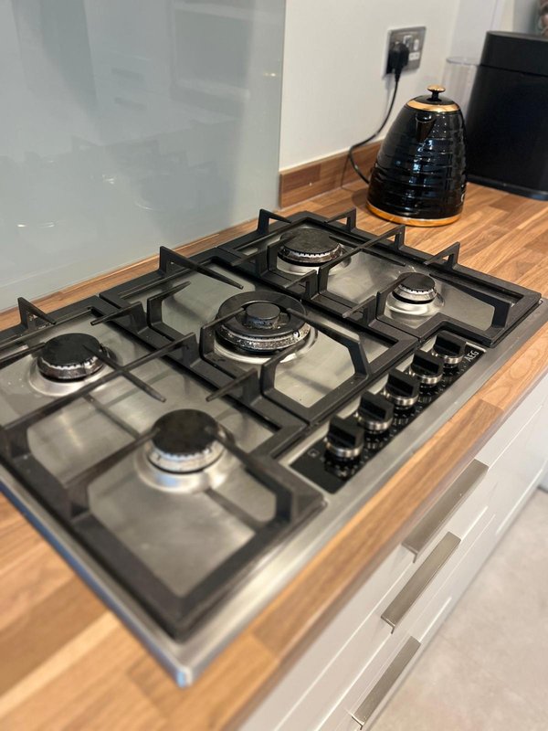 Modern kitchen with gas cooktop, wooden countertop, and black kettle on counter