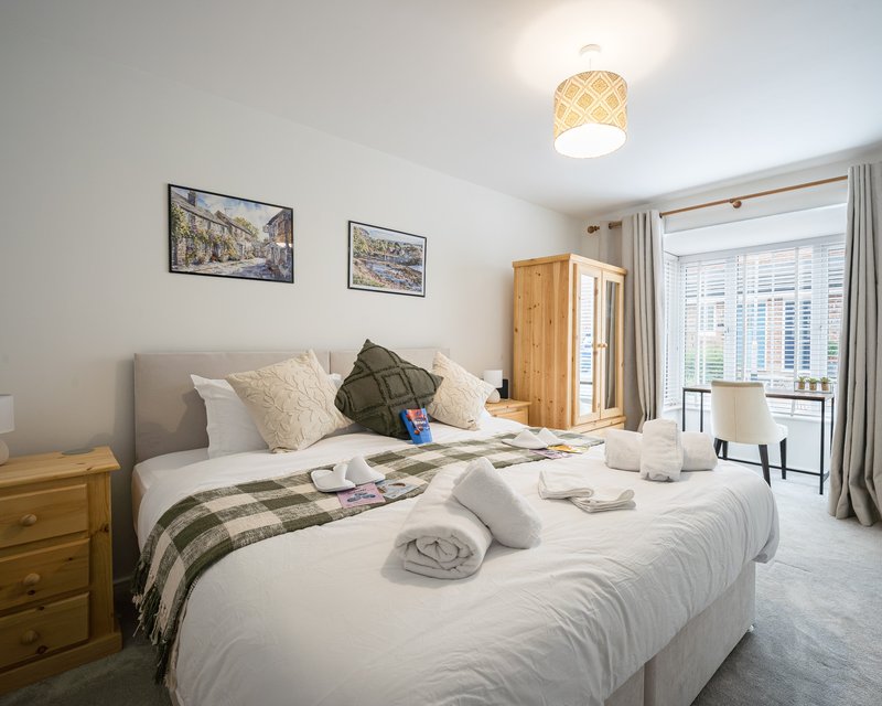 Bright bedroom with double bed, wooden nightstand, framed wall art, and balcony access