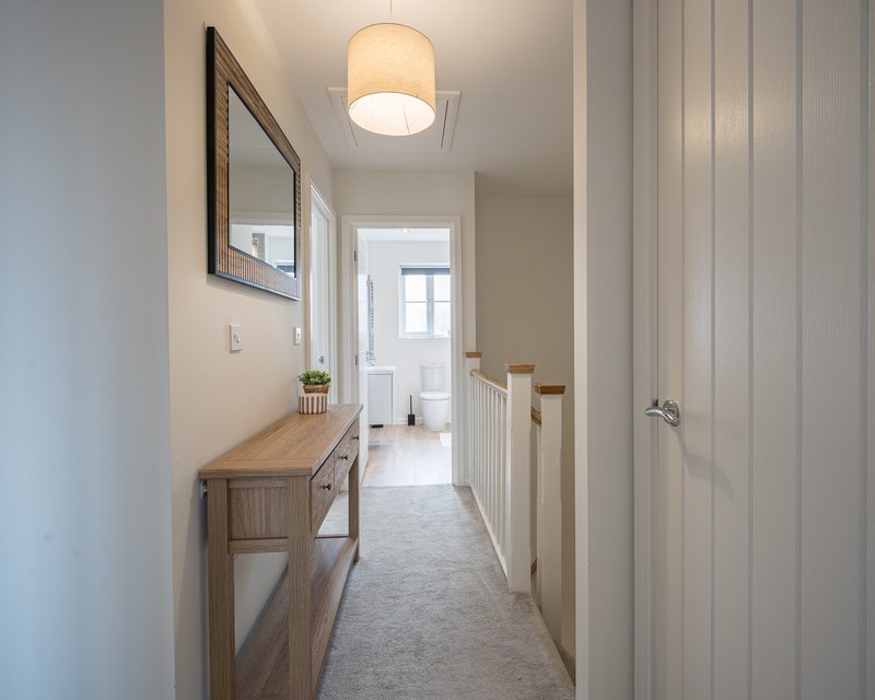 Bright hallway with wooden console table, framed mirror, ceiling light, and white doors