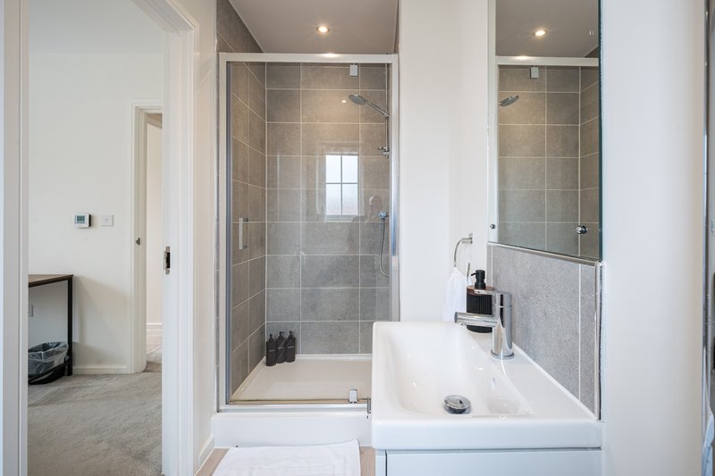 Modern bathroom with walk-in shower, white vanity, sink and toilet